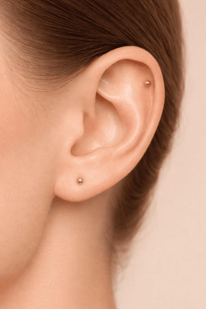 Piercing all’orecchio con gioielli dorati minimal su lobo e cartilagine